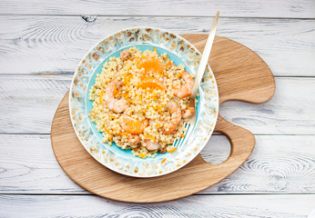 Healthy quinoa salad with fruits, vegetables and shrimps. Top view. Wooden background.