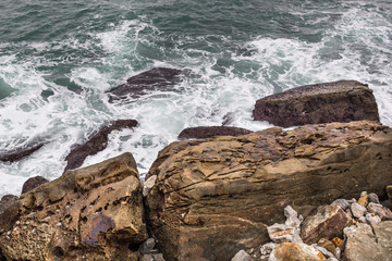 Stormy sea. Wave splash. The wave beats on the shore. Sea spray and foam around the stone. Water...