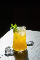 Delicious drink witn ice and mint on a black stone background.