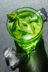 Delicious drink witn ice and mint on a black stone background.