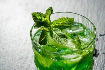 Delicious drink witn ice and mint on a black stone background.