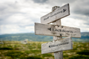 self-isolation lockdown quarantine text engraved on old wooden signpost outdoors in nature. Quotes, words and illustration concept.