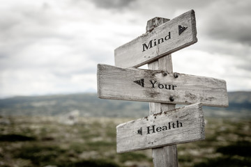 mind your health text engraved on old wooden signpost outdoors in nature. Quotes, words and illustration concept.