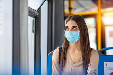 Fototapeta na wymiar Woman wearing a sterile protective medical mask against coronavirus, Covid-2019 Asian pandemic sars virus while going in a public bus in a European city street looking ahead.