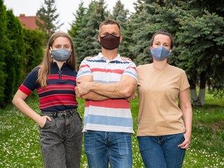 Family in protective face masks posing in the park