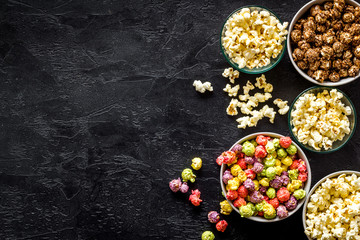 Colored popcorn in bowl on black background top view copy space