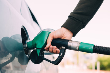 A man  manages his car with gasoline at a gas station. Hand and black refueling gun close-up.