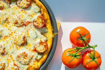 Cooked pizza with fresh tomatoes and sausage top view, close-up