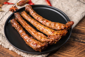 Marinated spicy duck neck on a black plate is extremely delicious to some people.