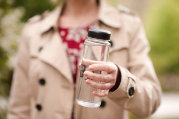 Woman holding plastic bottle with fresh water closeup. Heathy lifestyle. Wellness.