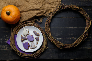 Pumpkin and Halloween cookies on white plate, sackcloth on black wooden background. Hallooween trick or treat concept. Copy space.