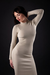 Woman in beige tight dress on black