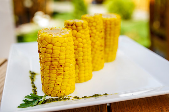 grilled sweet corn on white plate in the summer garden