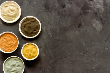 Yellow, red, white, blue and black cosmetic clay on grey table top view copy space