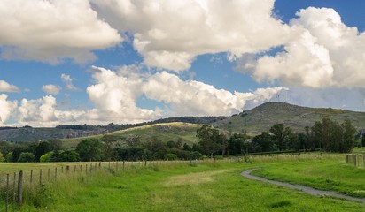 Fototapeta premium PAISAJE SERRANO BAJO UN CIELO CELESTE CON NUBES
