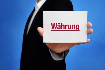 Währung. Anwalt hält Karte in der Hand. Beschriftung auf Schild zeigt Begriff. Hintergrund blau. Recht, Gesetz, Rechtsprechung