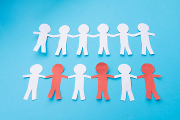 White and red paper people holding hands. Blue background