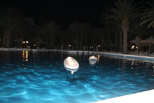 Lit Candles On Inflatable In Swimming Pool At Night