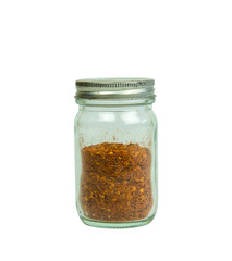 Cayenne pepper in a glass jar cover only half the bottle on white background