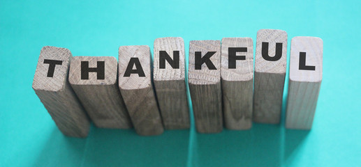Wooden cubes with word Thankful on a light blue background. Thank you feedback concept