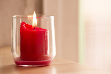Burning red candle inside a clear glass vase