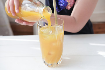 little girl pouring mango juice in a glass. iced frothy drink. tropical flavored juice. ice cubes in a glass. cold drinks for summer. close up view