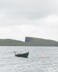 Morning view on lonely boat on cloudy Sorvagsvatn lake on cliffs of Vagar island, Faroe Islands, Denmark. Landscape photography