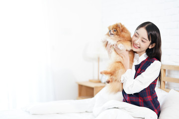 Pet Lover Concept. Girl and small dogs Pomeranian Spitz Looking forward. Asian girl and puppy looking forward in bed room. Space for text.