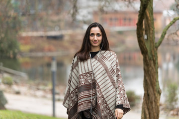 Young Indian woman model poncho for fall collection outdoors.