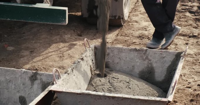 Fresh mortar, construction site, construction site in full swing, mortar flow, mortar for masonry, overflowed tank is standing on ground, male builder brought new mortar to construction site