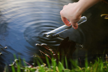 Scientist and biologist hydro-biologist takes water samples for analysis outdoors. Hand is collects...