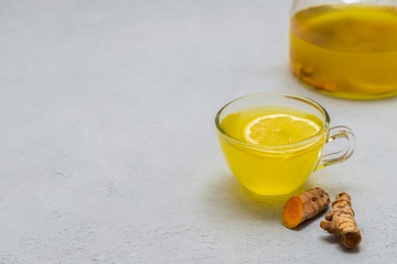 Easy delicious anti-inflammatory turmeric ginger tea on grey background with space for text