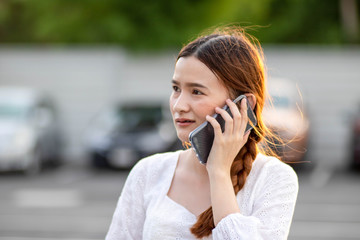 Displeased  and disappointed girl with a mobile phone stands in parking lot . In the evening the sunset was orange. copy space.