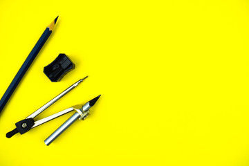 One black pencil crayon,a pencil sharpener and a compass attached to a pencil