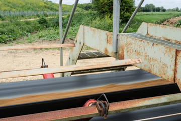 Shallow focus of a fast moving quarry conveyor belt showing the blurred sand and aggregate as it...