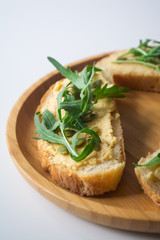 Sandwich of toasted bread slices with classic chickpea hummus spread, roasted pumpkin seeds and fresh arugula