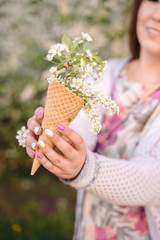 Beautiful waffle cone with ice cream decorated with flowers in the girl&rsquo;s hand with multi-colored bright manicure