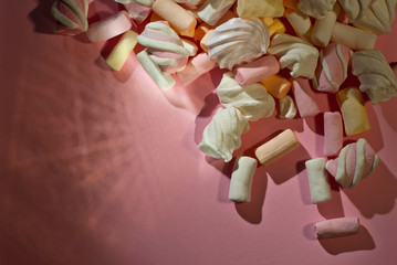 Lots of sweets on a pink background. White with orange marshmallows and bize close up.