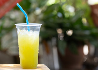Ready to drink sugarcane juice in plastic glasses on the wooden floor there is a bokeh backdrop.