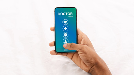 Man holding phone with online medical services on screen
