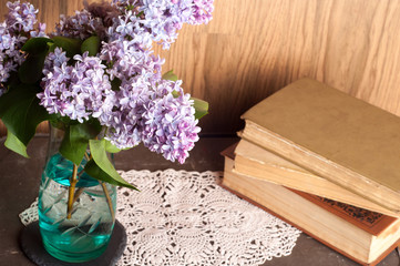 Home interior decor, bouquet of lilacs in a vase and books