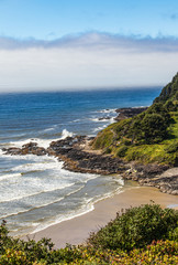 Vertical Image - waves crashing on the rocky coast in Oregon with wall of fog offshore. 