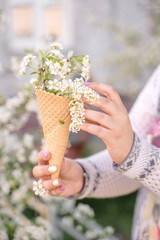 Beautiful waffle cone with ice cream decorated with flowers in the girl&rsquo;s hand with multi-colored bright manicure