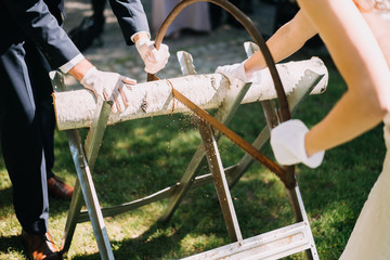 photo of a married couple sawing a trunk