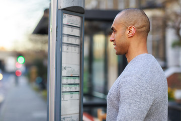 young man looking at the bus timetable
