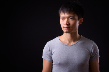 Portrait of young Asian man thinking and looking away