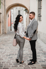 Charming girl with long brown hair and a man with a beard kissing on the background of the morning city. Newlyweds on their wedding day