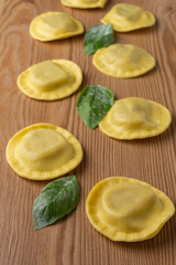 Top view of ravioli with mushrooms and basil, on wooden table, vertical
