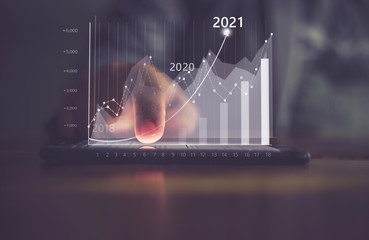 Augmented reality (AR) financial charts showing growing revenue In 2021 floating above digital...