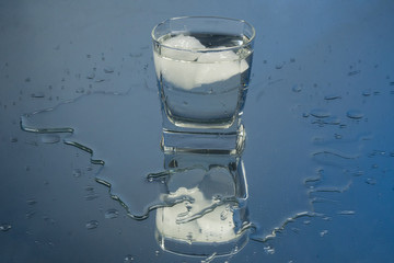 Bartender pouring up frozen vodka from a bottle into two shots glasses with ice cubes against black background. Barman pour of clear transparent alcohol drink rum tequila in shot-glass